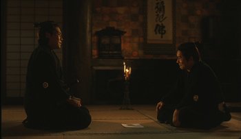 Movie still from “Taboo” (1999), directed by Nagisa Ôshima – A couple of people sitting on the ground in front of a candle; Wide shot, Over the shoulder angle