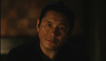 Movie still from “Taboo” (1999), directed by Nagisa Ôshima – A person wearing a black shirt; Close Up shot, Over the shoulder angle
