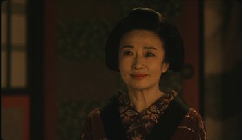 Movie still from “Taboo” (1999), directed by Nagisa Ôshima – An older asian woman wearing a black hat; Close Up shot, Low angle