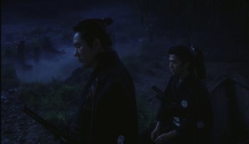 Movie still from “Taboo” (1999), directed by Nagisa Ôshima – Two men are standing in the dark holding swords; Medium shot, Over the shoulder angle