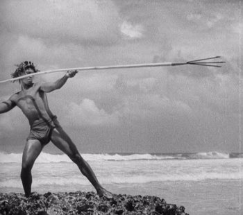 Movie still from “Tabu: A Story of the South Seas” (1931), directed by F.W. Murnau – A man is holding a spear in his hand; Wide shot, Low angle