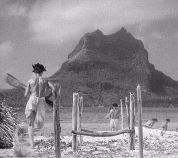 Movie still from “Tabu: A Story of the South Seas” (1931), directed by F.W. Murnau – A black - and - white photo of two people walking on the beach; Extreme Wide shot, Over the shoulder angle