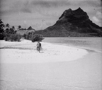 Movie still from “Tabu: A Story of the South Seas” (1931), directed by F.W. Murnau – A man riding a motorcycle on top of a sandy beach; Extreme Wide shot, High angle