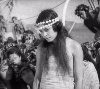 Movie still from “Tabu: A Story of the South Seas” (1931), directed by F.W. Murnau – A woman in a white dress with a flower headband; Medium shot, High angle