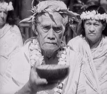 Movie still from “Tabu: A Story of the South Seas” (1931), directed by F.W. Murnau – An older man holding a wooden bowl in front of other men; Medium shot, High angle