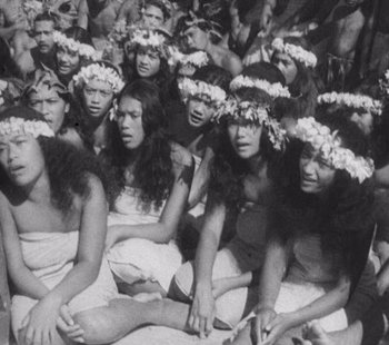 Movie still from “Tabu: A Story of the South Seas” (1931), directed by F.W. Murnau – A group of people sitting in a crowd wearing flower crowns; Medium shot, High angle