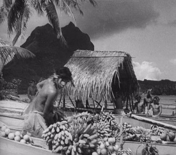 Movie still from “Tabu: A Story of the South Seas” (1931), directed by F.W. Murnau – An old photo of a man sitting in front of a shack; Wide shot, High angle