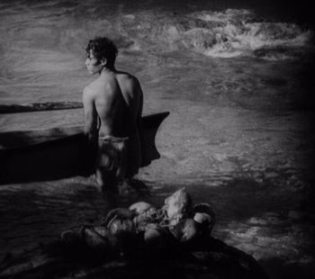 Movie still from “Tabu: A Story of the South Seas” (1931), directed by F.W. Murnau – A black and white photo of a man standing in the water; Wide shot, High angle