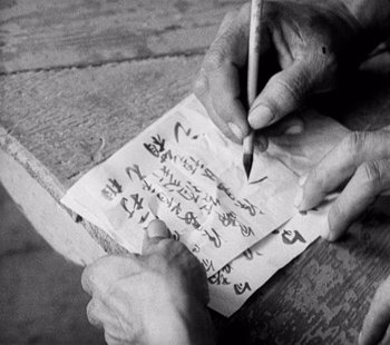 Movie still from “Tabu: A Story of the South Seas” (1931), directed by F.W. Murnau – A person writing on a piece of paper with a pencil; Extreme Close Up shot, Overhead angle