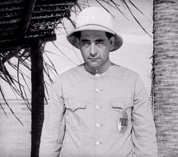 Movie still from “Tabu: A Story of the South Seas” (1931), directed by F.W. Murnau – A man wearing a white hat standing next to a palm tree; Medium shot, Low angle