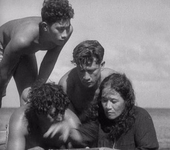 Movie still from “Tabu: A Story of the South Seas” (1931), directed by F.W. Murnau – A group of young men and women sitting next to each other on the beach; Medium shot, High angle