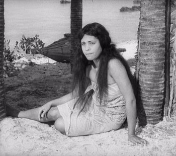 Movie still from “Tabu: A Story of the South Seas” (1931), directed by F.W. Murnau – A woman sitting on the ground next to a palm tree; Medium shot, High angle