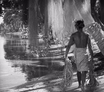 Movie still from “Tabu: A Story of the South Seas” (1931), directed by F.W. Murnau – A man walking in the water holding a net; Wide shot, Low angle