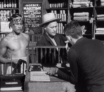 Movie still from “Tabu: A Story of the South Seas” (1931), directed by F.W. Murnau – A man is talking to two other men in a store; Medium shot, Over the shoulder angle