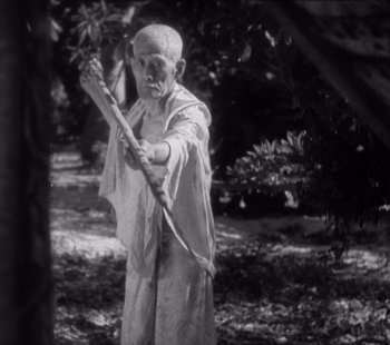 Movie still from “Tabu: A Story of the South Seas” (1931), directed by F.W. Murnau – An old man holding an arrow in the woods; Medium shot, Low angle