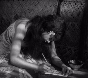 Movie still from “Tabu: A Story of the South Seas” (1931), directed by F.W. Murnau – A woman is writing on a piece of paper while sitting on a couch; Medium shot, High angle