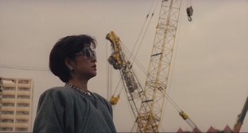 Movie still from “Taipei Story” (1985), directed by Edward Yang – A woman standing in front of a construction crane; Medium shot, Low angle