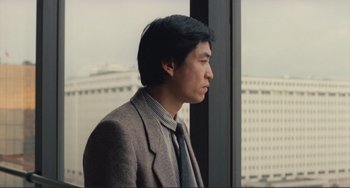 Movie still from “Taipei Story” (1985), directed by Edward Yang – A man wearing a suit and tie looking out a window; Close Up shot, Low angle