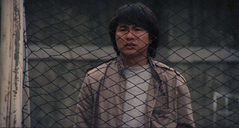 Movie still from “Taipei Story” (1985), directed by Edward Yang – A man standing in front of a chain link fence; Close Up shot, Low angle