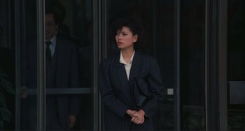 Movie still from “Taipei Story” (1985), directed by Edward Yang – A woman standing in front of a glass door; Medium shot, Over the shoulder angle