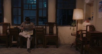 Movie still from “Taipei Story” (1985), directed by Edward Yang – A man sitting on a bench reading a newspaper; Wide shot, High angle