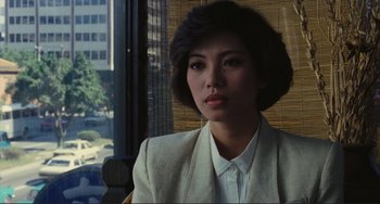 A woman in a white jacket sitting in front of a window