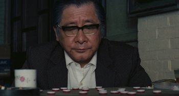 Movie still from “Taipei Story” (1985), directed by Edward Yang – An older man sitting in front of a bunch of small cups; Close Up shot, High angle