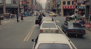 Movie still from “Taipei Story” (1985), directed by Edward Yang – A busy city street filled with cars and motorcycles; Extreme Wide shot, High angle
