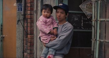 Movie still from “Taipei Story” (1985), directed by Edward Yang – A man holding a little girl in his arms; Medium shot, High angle