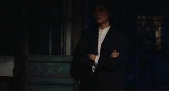 Movie still from “Taipei Story” (1985), directed by Edward Yang – A man in a suit standing with his arms crossed; Medium shot, Over the shoulder angle