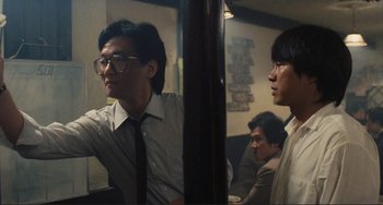 Movie still from “Taipei Story” (1985), directed by Edward Yang – A man in glasses and a tie is looking at himself in the mirror; Medium shot, Low angle