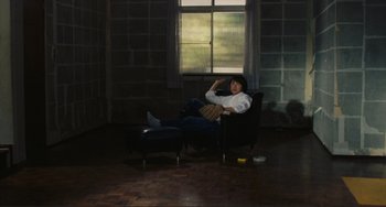 Movie still from “Taipei Story” (1985), directed by Edward Yang – A person sitting in a chair in a room; Wide shot, High angle