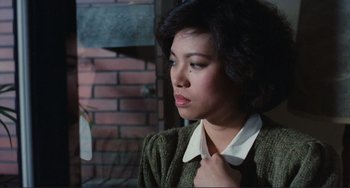 Movie still from “Taipei Story” (1985), directed by Edward Yang – A young woman adjusting her tie in a room; Close Up shot, Over the shoulder angle