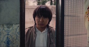 Movie still from “Taipei Story” (1985), directed by Edward Yang – A young man standing in front of a fence; Close Up shot, Over the shoulder angle
