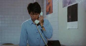 Movie still from “Taipei Story” (1985), directed by Edward Yang – A man holding a phone up to his ear; Medium shot, Over the shoulder angle
