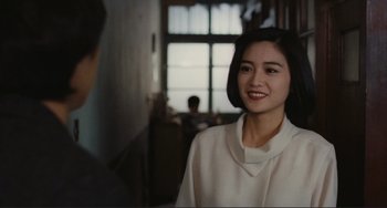 Movie still from “Taipei Story” (1985), directed by Edward Yang – A young woman smiles at the camera in front of a window; Close Up shot, Over the shoulder angle