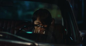Movie still from “Taipei Story” (1985), directed by Edward Yang – A man sitting in a car with a cigarette in his mouth; Close Up shot, High angle