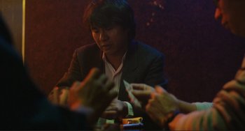 Movie still from “Taipei Story” (1985), directed by Edward Yang – A man sitting at a table with a cell phone in front of him; Medium shot, Over the shoulder angle