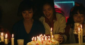 Movie still from “Taipei Story” (1985), directed by Edward Yang – Two young women sitting in front of a birthday cake with lit candles on it; Medium shot, High angle