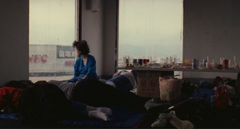 Movie still from “Taipei Story” (1985), directed by Edward Yang – A woman sitting on a bed looking out a window; Wide shot, High angle