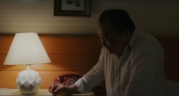 Movie still from “Taipei Story” (1985), directed by Edward Yang – An older man sitting at a dinner table writing on a piece of paper; Medium shot, High angle