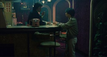 Movie still from “Taipei Story” (1985), directed by Edward Yang – Two people sitting at a table in front of a cell phone; Wide shot, High angle