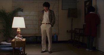 Movie still from “Taipei Story” (1985), directed by Edward Yang – A man standing in a room with his hands in his pockets; Wide shot, Low angle