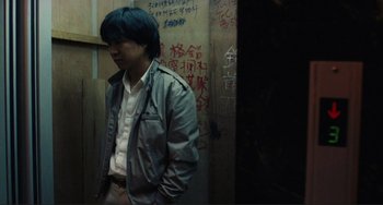 Movie still from “Taipei Story” (1985), directed by Edward Yang – A man standing in front of a wall with graffiti on it; Medium shot, Low angle