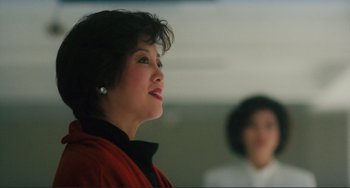 A woman in a red jacket looking up at something