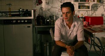 Movie still from “Take This Waltz” (2011), directed by Sarah Polley – A man sitting on a chair in a kitchen; Medium shot, Over the shoulder angle