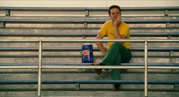 Movie still from “Take This Waltz” (2011), directed by Sarah Polley – A man sitting on some steps next to a bag of chips; Medium shot, Low angle