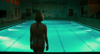 Movie still from “Take This Waltz” (2011), directed by Sarah Polley – A woman standing in front of a swimming pool at night; Wide shot, High angle