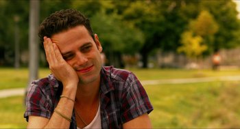 Movie still from “Take This Waltz” (2011), directed by Sarah Polley – A man sitting in the grass with his hand on his face; Close Up shot, Over the shoulder angle