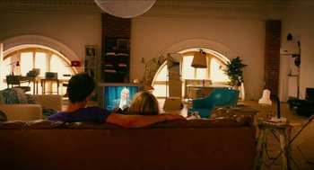 Movie still from “Take This Waltz” (2011), directed by Sarah Polley – Two people are sitting on a couch watching television; Wide shot, Over the shoulder angle